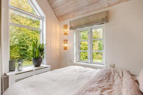 a white bedroom with a bed and two windows at Thatched country escape - Aarhus in Lystrup