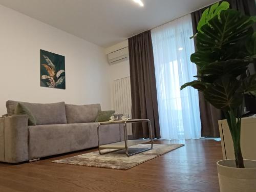 a living room with a couch and a potted plant at Planet Green Residence in Niš