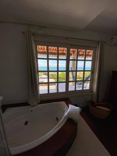 a large bath tub in a bathroom with a window at Pousada Chic N Choc in Morro de São Paulo