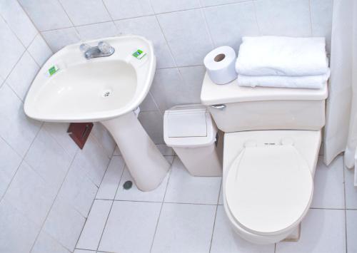 a white bathroom with a toilet and a sink at Hotel La Quinta de Allison in Lima