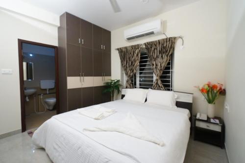 a bedroom with a large white bed and a bathroom at Krishna Vibe Service Apartment in Tiruchchirāppalli