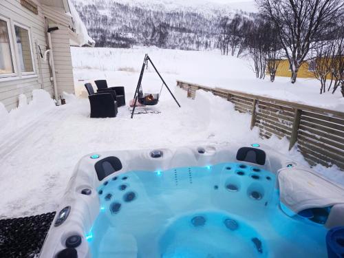 a hot tub in the snow next to a house at Blabergan Lodge in Nord-Lenangen