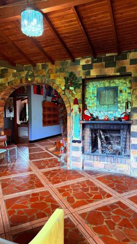 una chimenea de piedra en una habitación con suelo de piedra en Finca 5 Continentes - Cerca MatroCable ARVI, en Guarne