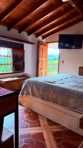 a bedroom with a large bed and a large window at Finca 5 Continentes - Cerca MatroCable ARVI in Guarne