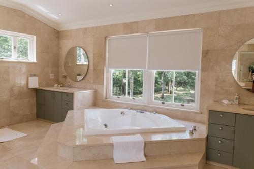 Un baño grande con bañera y ventana. en Klein Champagne Guesthouse and Cottages, en Franschhoek