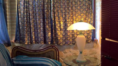 a lamp on a table next to a window with curtains at Tamerici House in Montecastrilli
