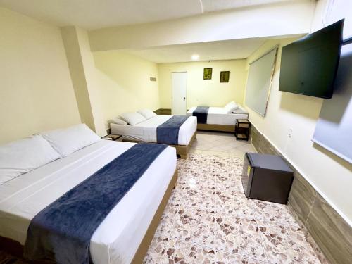 a hotel room with two beds and a tv at Hotel Estadio 80 in Medellín