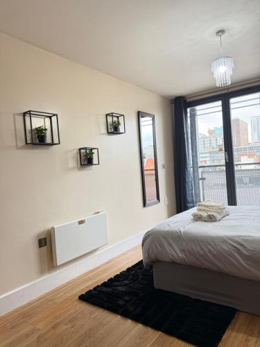 ein weißes Schlafzimmer mit einem Bett und einem Fenster in der Unterkunft Nexus - Top Floor City Views, Balcony & Parking in Birmingham