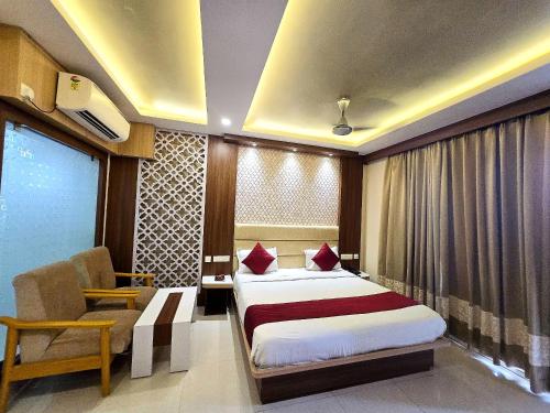 a hotel room with a bed and a chair at Kuber - Palace Premium # Restaurant- Lift and Free Parking Facilities - Fully Air Conditioning Premium Room in Puri