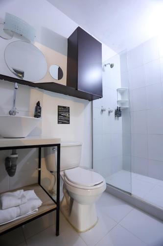 a bathroom with a white toilet and a shower at Pixel House Hotel in Medellín