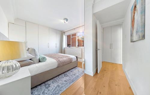 a white bedroom with a bed and a window at PANORAMIC Apartment with Terrace on HARRODS in London
