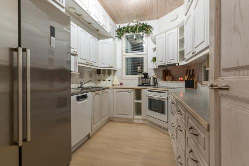 a kitchen with white cabinets and a stainless steel refrigerator at Arctic Escape Near Santa Claus Village in Rovaniemi