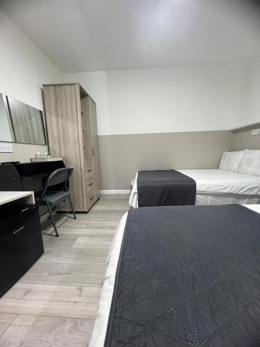a hotel room with two beds and a desk at Plaza London Hotel in London