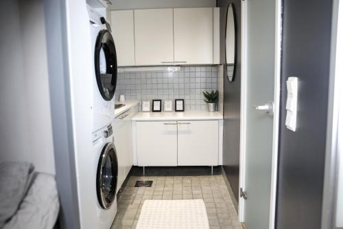 eine Küche mit weißen Schränken und einer Waschmaschine und einem Trockner in der Unterkunft Villa Rajaportti Loft with lake view and free front door parking&electric car plugs in Tampere