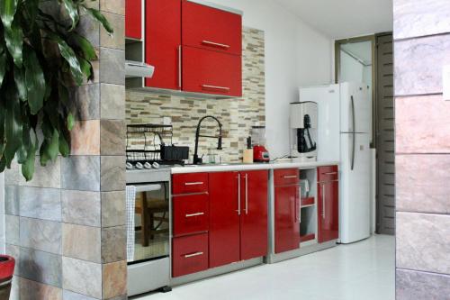 a kitchen with red cabinets and a white refrigerator at Loft lujo estilo y diseño, alberca, Cuernavaca somos los únicos en ofrecerte 2 jacuzzis tipo Spa con agua caliente y sistema de hidromasaje, alberca con calefacción ecológica, amplia cama de alberca, 3 pantallas, terraza privada con asador de carbon, WiFi in Cuernavaca