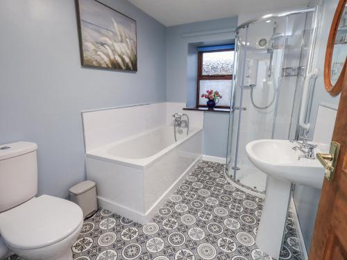 a bathroom with a tub and a toilet and a sink at Christine's Stable in Crosby Ravensworth