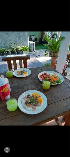 three plates of food on a wooden table at บ้านอังกาบ Aungkab homestay in Ban Muang Len