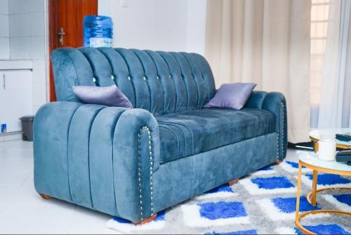- un canapé bleu avec deux oreillers dans le salon dans l'établissement Lakeview Luxe Haven, à Kisumu