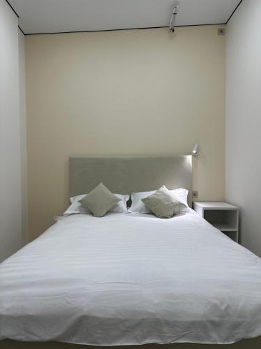 a large white bed with white sheets and pillows at Qonys Hostel in Atyrau