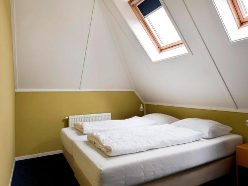 a bedroom with a white bed with two windows at Detached house in Vlagtwedde with sauna in Vlagtwedde
