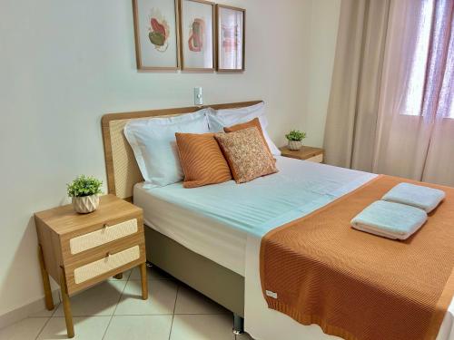 una camera da letto con un grande letto con cuscini e un comodino di Apê charmoso a 2km do Centro - 4km do Pq Aquático ad Águas de Lindóia