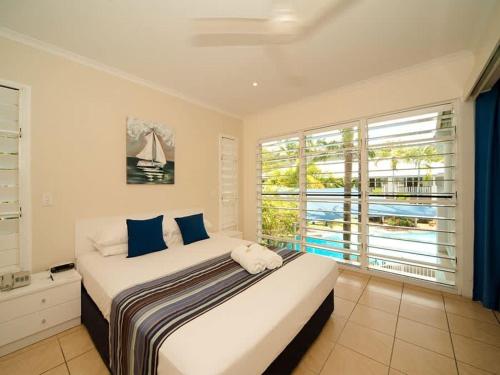 a bedroom with a large bed and a large window at Tropic Sol in Airlie Beach