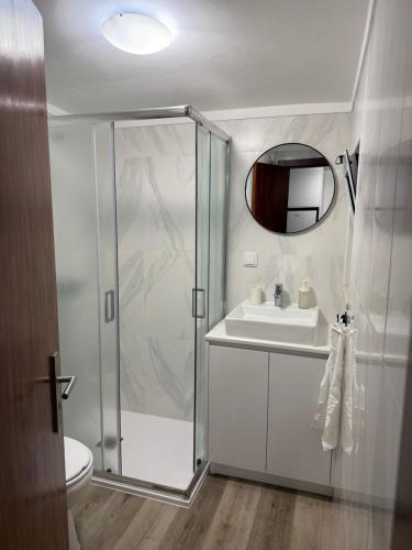a bathroom with a shower and a sink and a mirror at Casa da Ti'nês in Bombarral