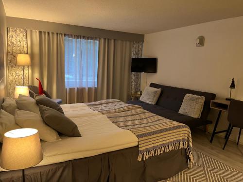 a bedroom with a large bed and a couch at Hotel Yöpuu in Kemi