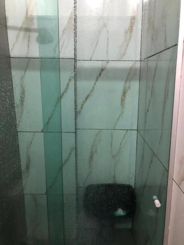 a tiled bathroom with a glass wall with a toilet at suíte climatizada com sala e cozinha familiar in Belém