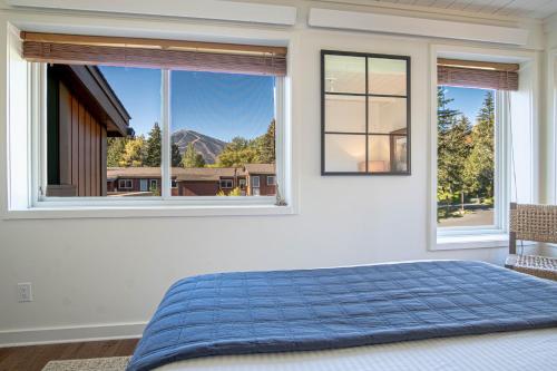 una camera con un letto blu e due finestre di Atelier Alpine - Modern 2BD Condo w/Baldy Views a Sun Valley