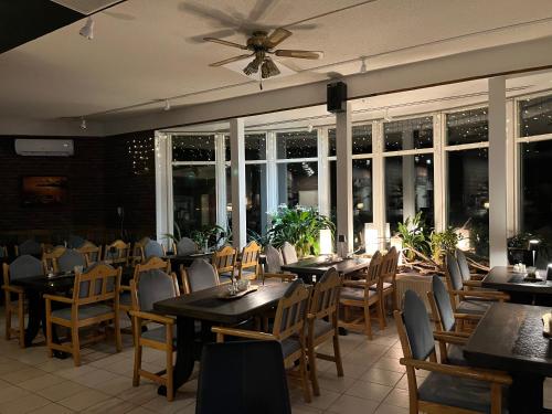 a dining room with tables and chairs and windows at Hotel Yöpuu in Kemi