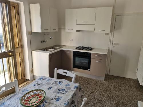 a kitchen with white cabinets and a table and a sink at Casa Fuxia in Marina di Cecina