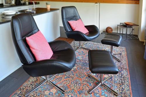 drei schwarze Stühle mit roten Kissen auf einem Teppich in der Unterkunft Chesa Filomela in Bever