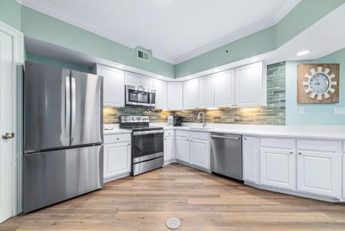 a kitchen with white cabinets and a stainless steel refrigerator at Summer House Unit 602A in Orange Beach