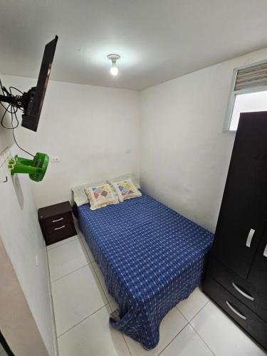 Un pequeño dormitorio con una cama azul en la esquina en Apartaestudios centro ibague, en Ibagué