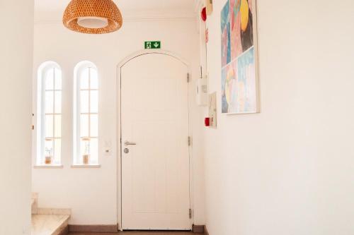 un couloir blanc avec une porte et des fenêtres blanches dans l'établissement Arrifana Surf Camp, à Aljezur