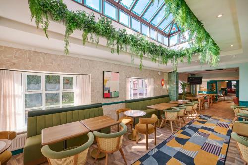 a restaurant with tables and chairs and windows at Garner Hotel Birmingham South East by IHG in Birmingham