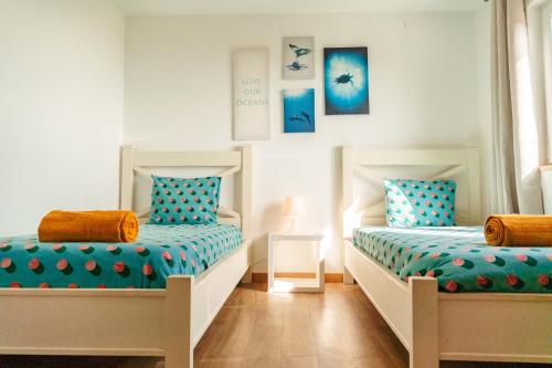 deux lits dans une chambre avec du bleu et du blanc dans l'établissement Arrifana Surf Camp, à Aljezur