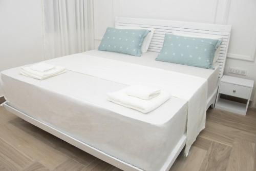 - un lit blanc avec 2 oreillers bleus dans l'établissement Zeitahomes, à Cotonou