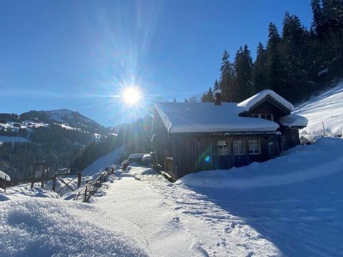 ein schneebedecktes Haus mit der Sonne dahinter in der Unterkunft Ferienhaus Schönenmatte in Zweisimmen