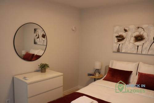 een slaapkamer met een bed en een spiegel aan de muur bij Cantinho da Bea I in Angra do Heroísmo