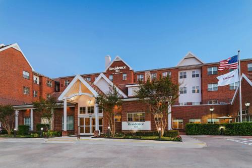 a large red brick building with an american flag at Residence Inn Dallas DFW Airport South/Irving in Irving