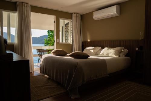 a bedroom with a bed with a view of the ocean at Pousada Papiro Boutique in Abraão
