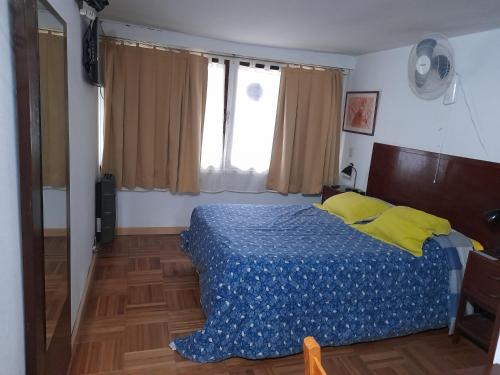 - une chambre avec un lit doté d'une couverture bleue et d'oreillers jaunes dans l'établissement Tu Alojamiento en Mar del Plata, à Mar del Plata