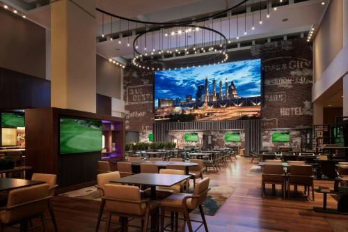 a restaurant with tables and chairs and a large screen at Kansas City Marriott Downtown in Kansas City