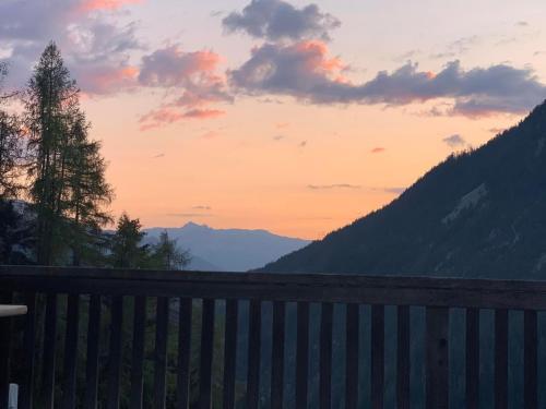 un coucher de soleil dans les montagnes avec une clôture en bois dans l'établissement Neuwertiges 2 Zi Ferienchalet 55M2, à Monstein
