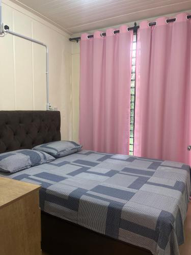 Schlafzimmer mit einem Bett und rosa Vorhängen in der Unterkunft Casinha na serra para até 4 pessoas in Nova Petrópolis