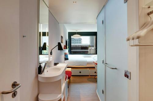 a bathroom with a sink and a bedroom with a bed at citizenM Seattle South Lake in Seattle