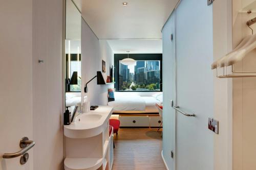 a bathroom with a sink and a bedroom with a bed at citizenM Seattle South Lake in Seattle