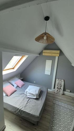 a bedroom with a bed with two pillows and a window at Charmante maison près des bords de la Loire in Beaufort-en-Vallée